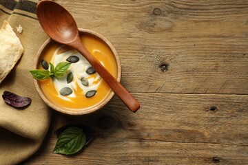 Delicious pumpkin soup served on wooden table, top view. Space for text