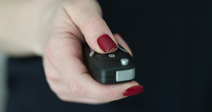 Woman driver presses a button on black car key fob