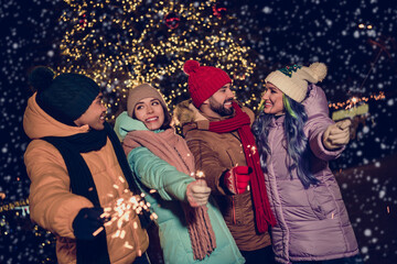 Photo of positive good mood four buddies wear windbreakers firing xmas bengal fires together...