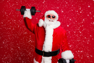 Active life for pensioners. Photo of retired old man white beard lift heavy dumbbells smiling strong grandpa concept wear santa costume sunglass headwear isolated red color background