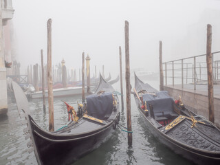 Gondolas moored in the pier in Venice in a foggy day. © Luis