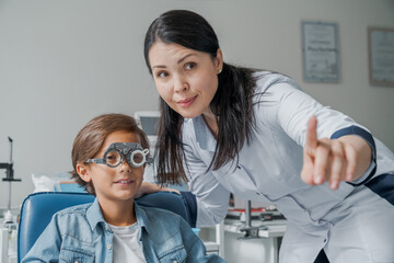 Eye examination. Children's doctor putting trial frame on little boy in clinic