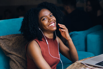 Fototapeta premium Portrait of happy excited female student in electronic earphones feeling excited from good motivation audio book listening via education application on laptop computer connected to 4g wireless