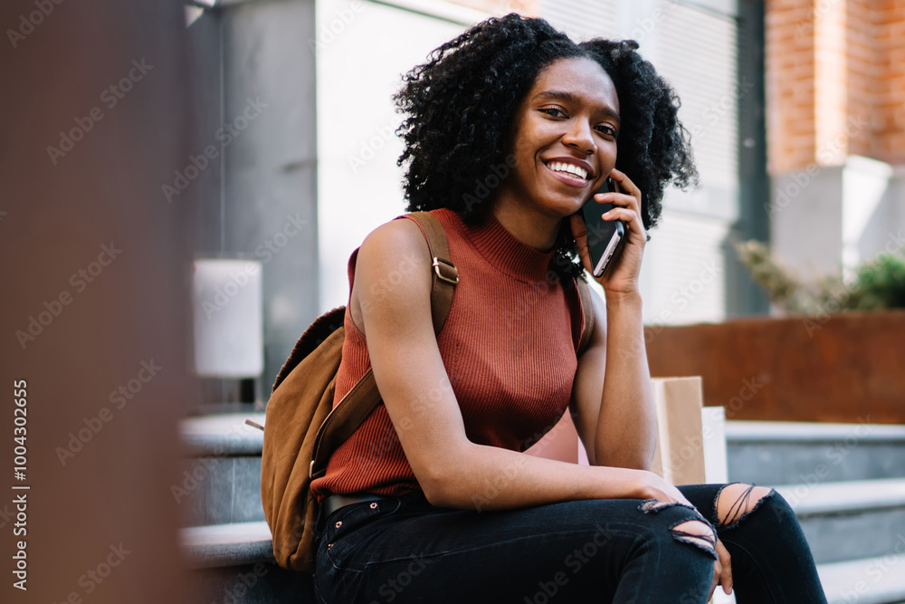 Poster portrait of cheerful female student dressed in casual apparel smiling at camera while communicating 