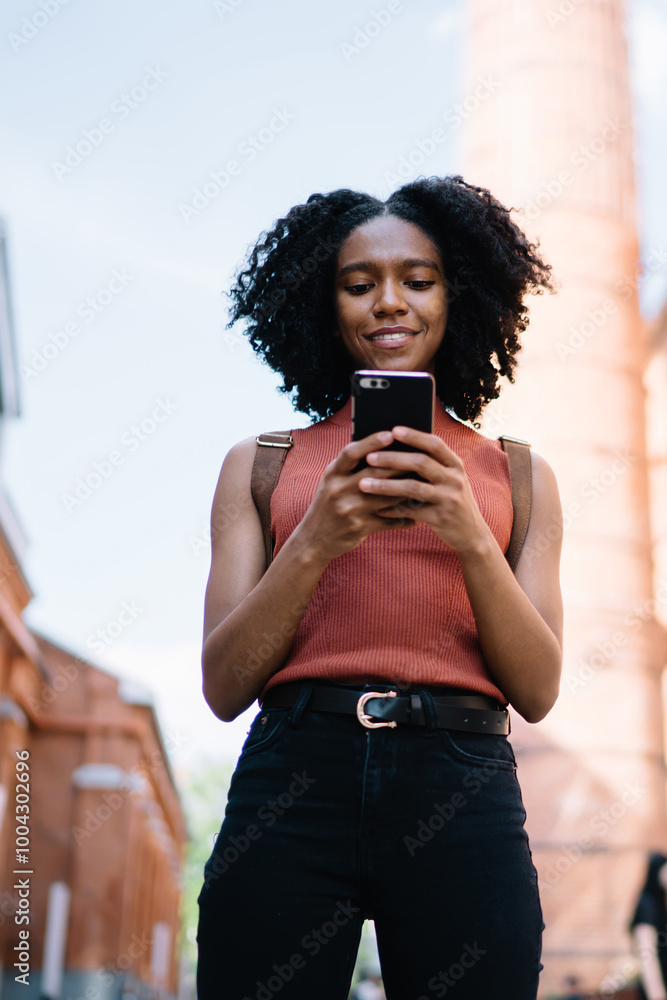 Poster below view of millennial hipster girl playing online games via cellular application while waiting fr