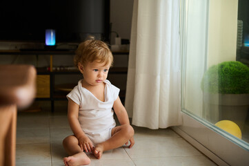 Curious toddler sitting by a window in a bright room