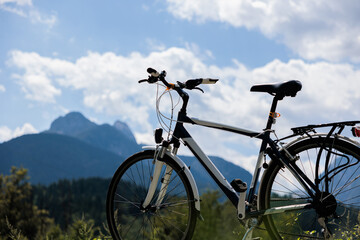 viaggiare o fare attività sportiva in bicicletta. bici da città in primo piano, ambiente di montagna, di giorno, in estate, illuminato dal sole e con colori brillanti sullo sfondo. 