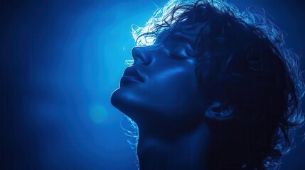silhouette of a man against a deep blue backdrop with light haloing around his profile creating a dramatic and introspective mood that captivates the viewer