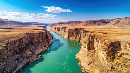 A river flows through a canyon with a blue sky in the background