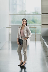 A stylish businesswoman in formal attire walks confidently through a modern office hallway, embodying professionalism, leadership, and success.