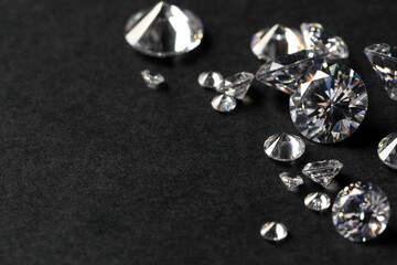 Many beautiful shiny diamonds on black table, closeup. Space for text