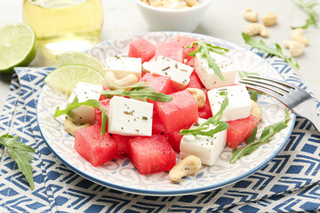 Delicious watermelon salad with feta cheese, cashew nuts and spices served on light table, closeup