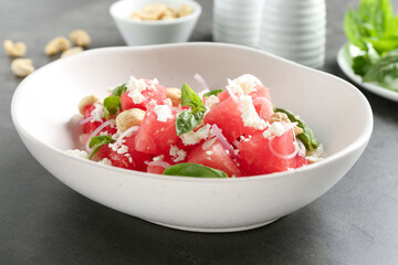 Tasty salad with watermelon, feta cheese and basil on black table