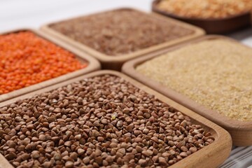 Different types of cereals and legumes on white table, closeup
