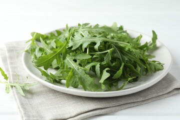 Fresh green arugula leaves on white table, closeup