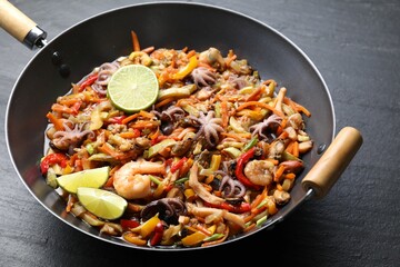 Stir-fry sea food in wok on grey textured table, closeup