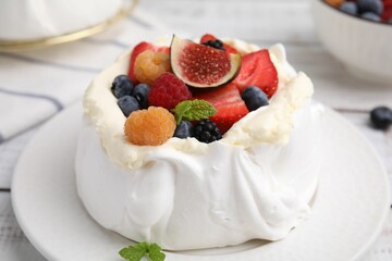 Pavlova cake (meringue dessert) with whipped cream, fresh berries, fig and mint on table, closeup