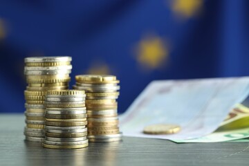 Stacks of coins and euro banknotes on grey textured table, closeup