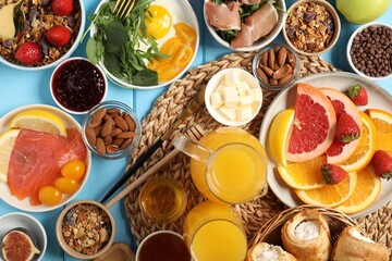 Different tasty food served for brunch on light blue wooden table, flat lay