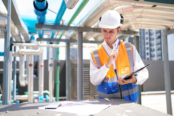 Technician writing on clipboard for checking pipeline valves or water tank area at urban industrial...