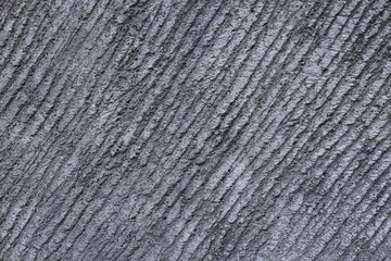 Grey concrete surface with diagonal relief. Pattern with diagonal stripes. Point embeddings in wall. Concept of strength, obstruction. Decoration of buildings and landscape.