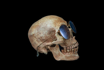 Human skull wears sunglasses on black background
