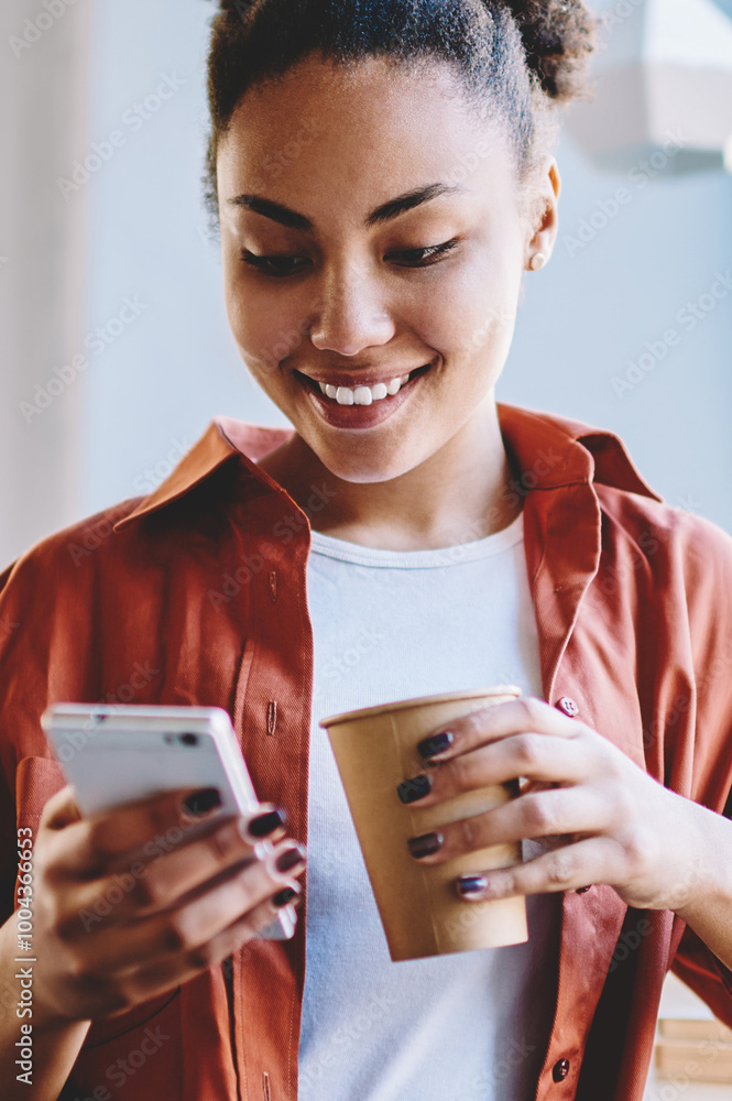 Poster happy dark skinned hipster girl sending sms message via smartphone device while enjoying caffeine be