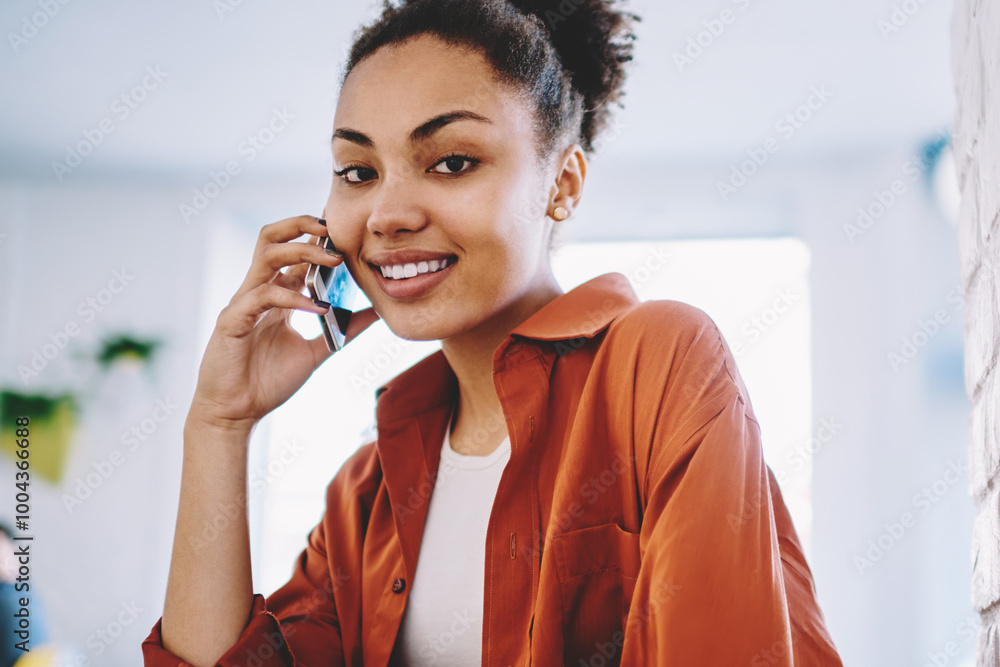 Poster portrait of cheerful dark skinned hipster girl using public internet connection on modern mobile pho