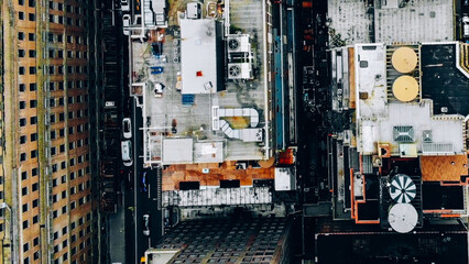 Aerial view of New York downtown building roofs with water towers. Bird's eye view from helicopter of cityscape metropolis infrastructure, traffic cars moving on city streets and district avenues