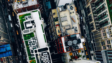 Obraz premium Aerial view of New York downtown building roofs with water towers. Bird's eye view from helicopter of cityscape metropolis infrastructure, traffic cars moving on city streets and district avenues