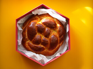 Round fresh challah in a Magen David shaped box on a yellow background. Jewish New Year. Traditional homemade aromatic pastries for the holiday