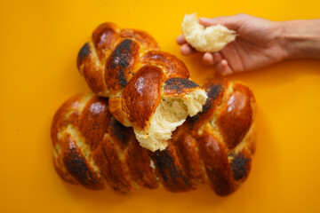 fresh homemade challah bread on a bright background, a piece of bread in the hand
