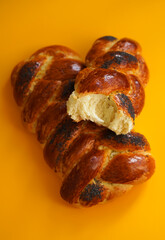 Two fresh homemade challah breads on a yellow background