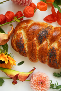 Close-up, appetizing yeast roll challah bread on a background of flowers.