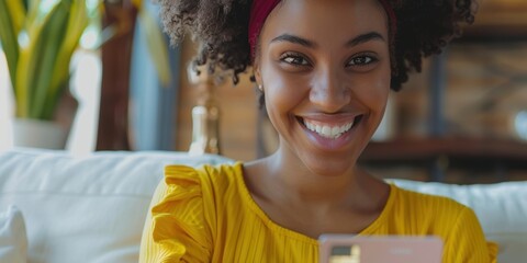 Joyful businesswoman using her phone with a credit card for online shopping at home, expressing excitement as a customer on a financial platform