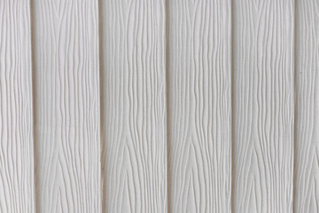 Fototapeta premium Close-up of white vertical plastic planks with wooden texture, highlighting the detailed imitation of natural wood. The subtle, intricate design perfect for various decor and artistic applications.