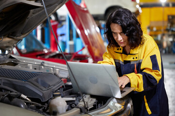 Mechanic or worker using laptop computer for checking and fixing a car in automobile repair shop