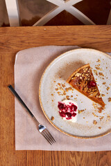 top view of a wooden table top with a piece of pumpkin pie on a fork on a ceramic plate