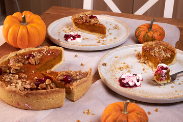 top view of a wooden table top with pumpkin pie and ceramic plates with pieces of pie on them