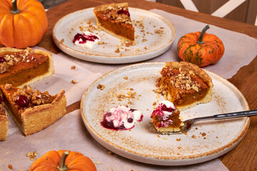top view of a wooden table top with a piece of pumpkin pie on a fork on a ceramic plate