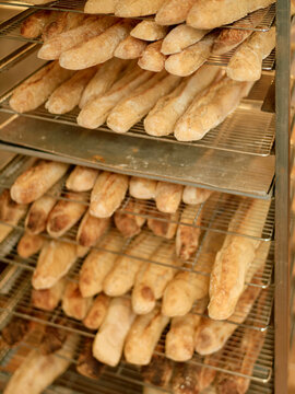 Freshly baked baguettes on display in a bakery's wooden shelving unit.