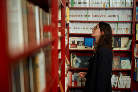 Woman browsing books on shelves at a library or bookstore.