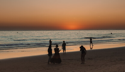 Group of people walking on the beach at sunset © Raquel