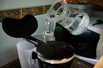 Filling a coffee maker with water in a kitchen setting