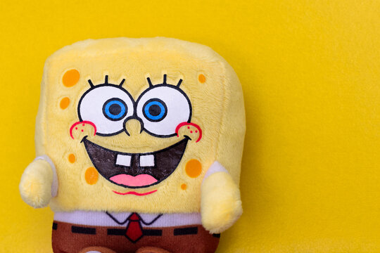 Small plush SpongeBob SquarePants on a yellow background. Funny Sponge Bob toy