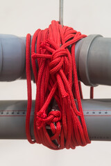 Dettaglio di due tubi grigi di plastica legati da una piccola corda rossa © Andrea Vismara