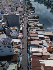 Vertical drone view along the waterfront street and rooftops of a densely populated area. The canal reflects the dramatic sky and buildings on a sunny clear day. 