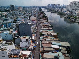 Drone view along the waterfront street and rooftops of a densely populated area. The canal reflects the dramatic sky and buildings on a sunny clear day. 