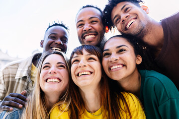 Young group of happy people having fun together on summer vacation. Millennial students from different cultures bonding and enjoying time outdoors. Youth community concept.