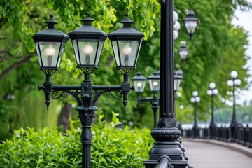 Classic black street lamps line park pathway surrounded by vibrant green trees, overcast lighting...